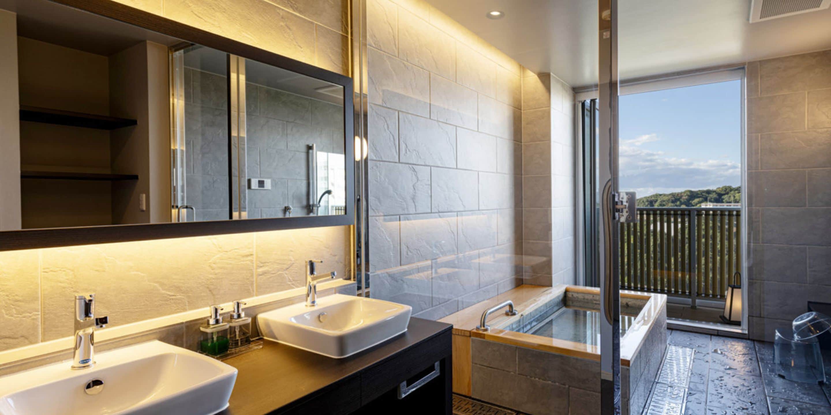 Un baño moderno con dos lavamanos, un espejo grande y una bañera.