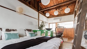 A bedroom with a wooden ceiling, a bed with white and teal bedding, a green nightstand, a black chair, and a view of the outside. - nid Tani6 House (Osaka)