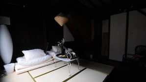 A minimalist room with a sofa, a small table with a tray, and a hanging light fixture. - nid Tani6 House (Osaka)