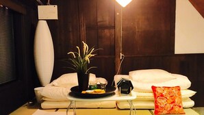 A neatly arranged bedroom with a bed, pillows, a bedside table with a lamp, a small plant, and a tray with items. - nid Tani6 House (Osaka)