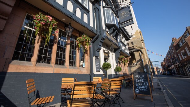 A pub with outdoor seating, a signboard, and hanging flower baskets. - The Cross Keys (Knutsford)