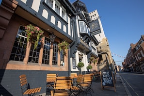 A pub with outdoor seating, a signboard, and hanging flower baskets. - The Cross Keys (Knutsford)