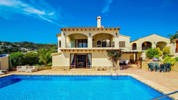 Eine Villa im mediterranen Stil mit Swimmingpool, Sitzgelegenheiten im Freien und Blick auf die umliegende Landschaft.