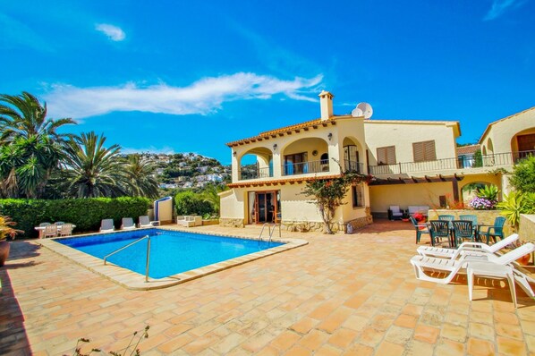 Une villa de style méditerranéen dotée d’une piscine, d’un espace salon extérieur et offrant une vue sur le paysage environnant.