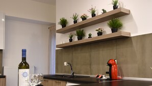 A modern kitchen with wooden shelves holding potted plants, a wine bottle, and glasses on a tray.