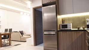 A modern kitchen with a built-in microwave, stainless steel refrigerator, and wooden cabinets.