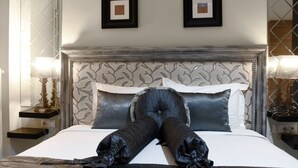 A neatly made bed with a decorative headboard, two bedside tables with lamps, and framed pictures on the wall.