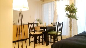 Una habitación de hotel con una cama, una mesa de comedor con sillas, una lámpara y una planta en maceta.