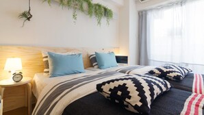 Una cama doble con almohadas azules a rayas, una mesita de noche con lámpara y un aire acondicionado instalado en la pared.