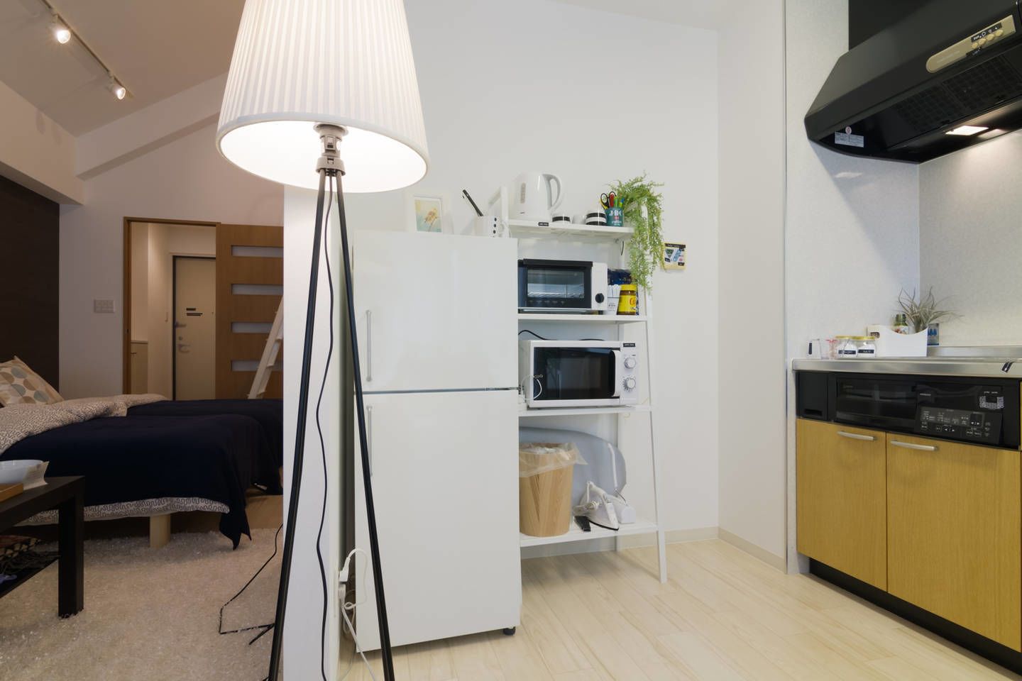 Eine kompakte Küche mit Mikrowelle, Toaster und Geschirrspüler, einem kleinen Kühlschrank und einer Stehlampe.