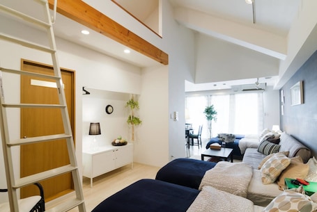 A modern room with a loft bed, a desk, and a dining area.