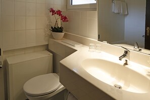 A bathroom with a toilet, sink, and a potted orchid. - Landhaus Wald und See (Biersdorf am See)