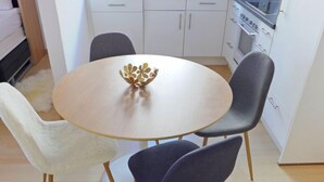 Un'area pranzo con un tavolo rotondo e quattro sedie, una piccola ciotola decorativa sul tavolo, e una cucina sullo sfondo.