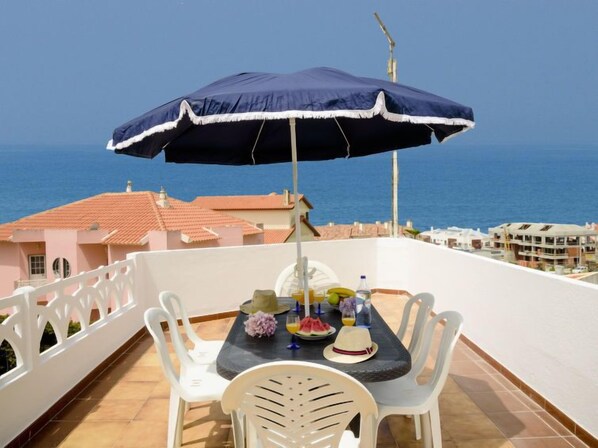 A balcony with a table set for two, overlooking the sea.