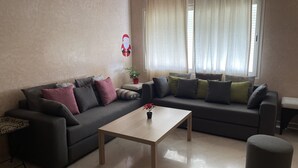 Una sala de estar con un sofá gris, una mesa de centro de madera y un otoman gris.