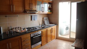 Cocina con gabinetes de madera, estufa a gas, horno, pileta y ventana con vista a un lavadero.