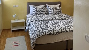 Un dormitorio con cama, mesita de noche, lámpara y una lámpara colgante.