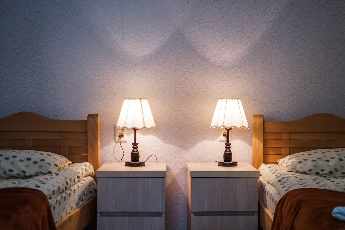 Dos camas individuales con cabeceros de madera, cada una con una mesita de noche y una lámpara.