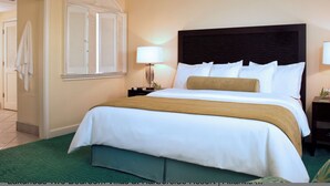 A hotel room with a large bed, a nightstand, a lamp, and a view of the hallway. - 1 Premium Villa - master bedroom, 1 bath, and full kitchen (Paradise Island)