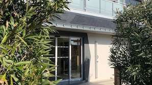 Una casa moderna de dos pisos con entrada de vidrio y un balcón.