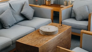 Una sala de estar moderna con un sofá gris, una mesa de centro de madera y un jarrón con flores blancas.