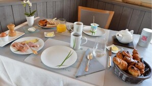 Una preparación para el desayuno con platos de comida, una tetera y una cesta de cruasanes.