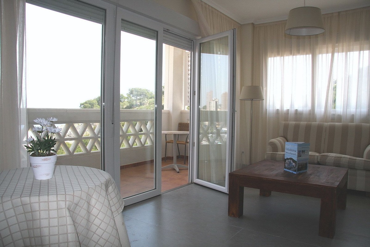 Un balcon avec une plante en pot, un canapé, une table et une lampe.