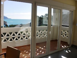 A balcony with a view of the sea and mountains.