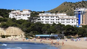 Uma praia com um hotel chamado "Hotel Balesol" ao fundo, com vários andares e varandas.