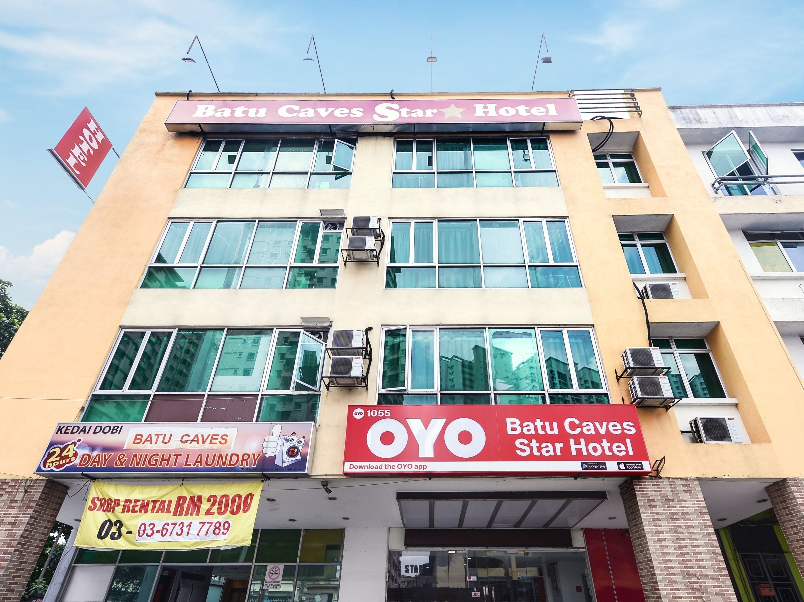 A hotel named Batu Caves Star Hotel with multiple signs advertising services like laundry and a rental shop.