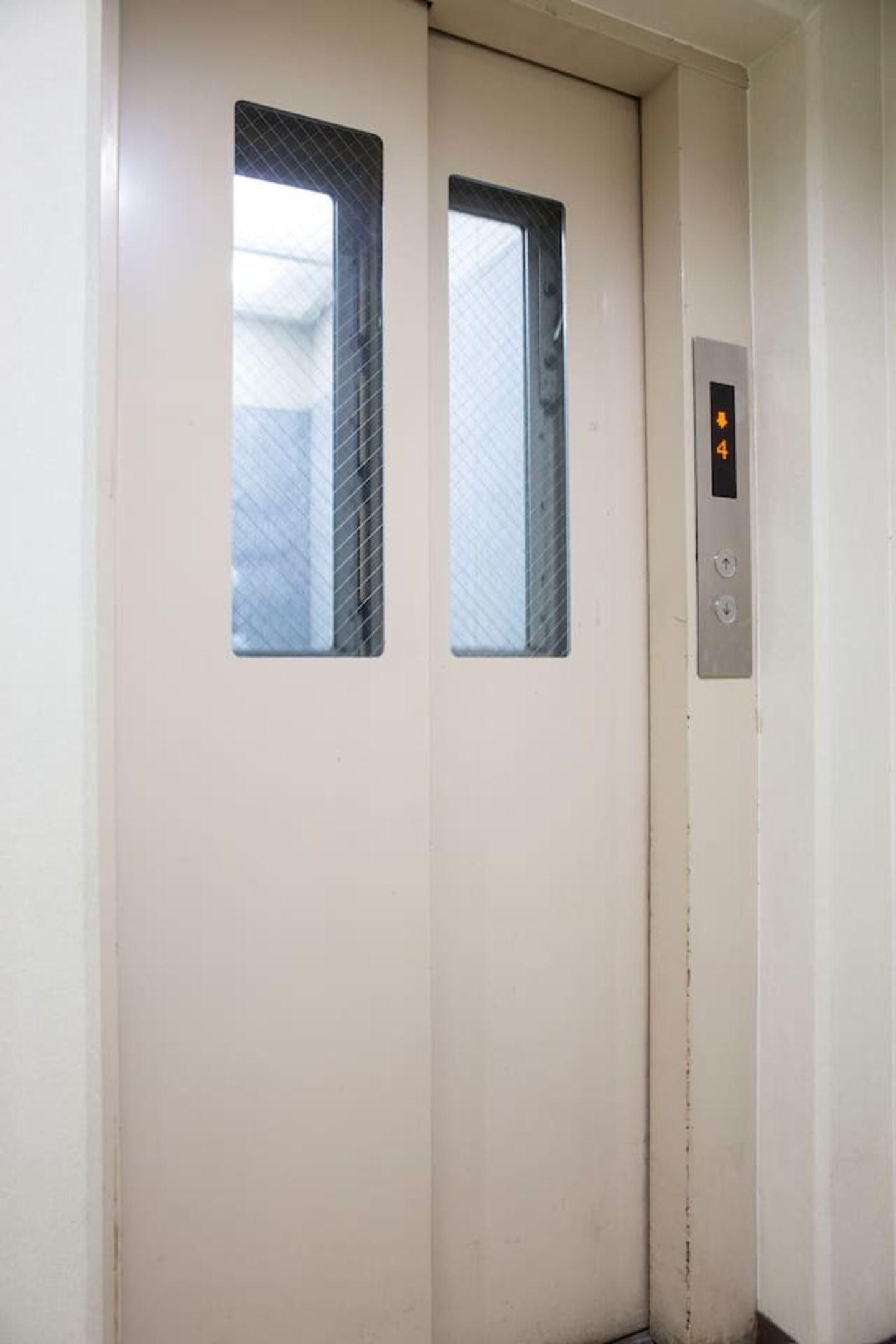 An elevator with two windows and a control panel with a digital display.