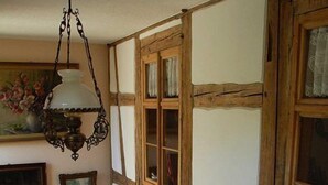 A room with exposed wooden beams, a staircase with a wrought iron railing, and a hanging light fixture.