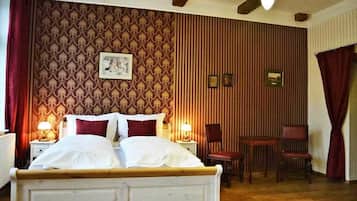A bedroom with a bed, two bedside tables, a chair, and a small table.
