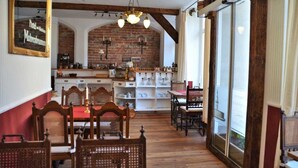 A restaurant with wooden furniture, brick walls, and a brick fireplace.
