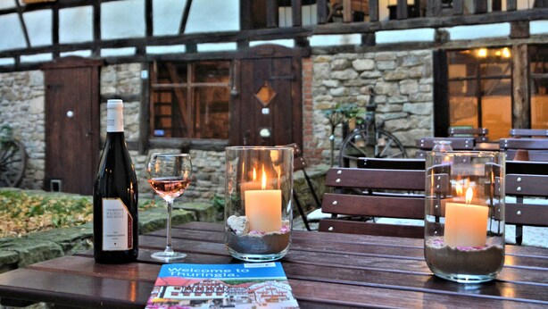 A table with a bottle of wine, a glass of wine, and two candles in glass holders.