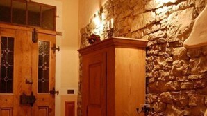 A stone wall with a wooden cabinet and a table with a basket of apples.