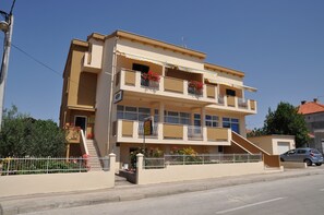 A multi-story building with balconies, a staircase, and a gated entrance. - Apartments Amico (Zadar)