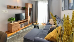 Una sala de estar moderna con sofá, televisor, mueble de madera y una pequeña mesa.