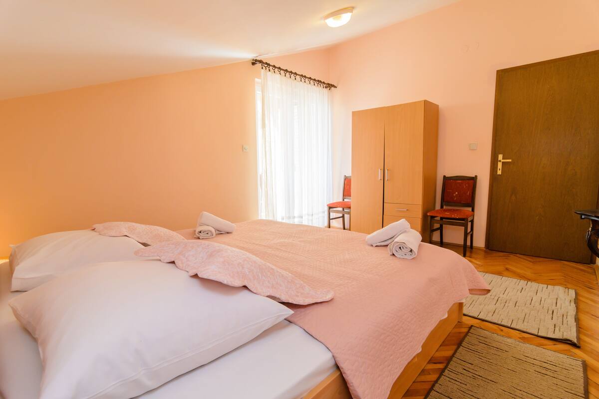 A bedroom with a bed, a wardrobe, a chair, and a door.
