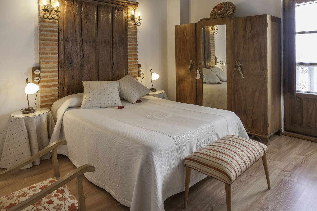 Een slaapkamer met een groot bed, een houten garderobe en bedlampjes.
