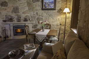 Una sala de estar acogedora con una chimenea de piedra, una mesa con un jarrón de flores y un sofá.