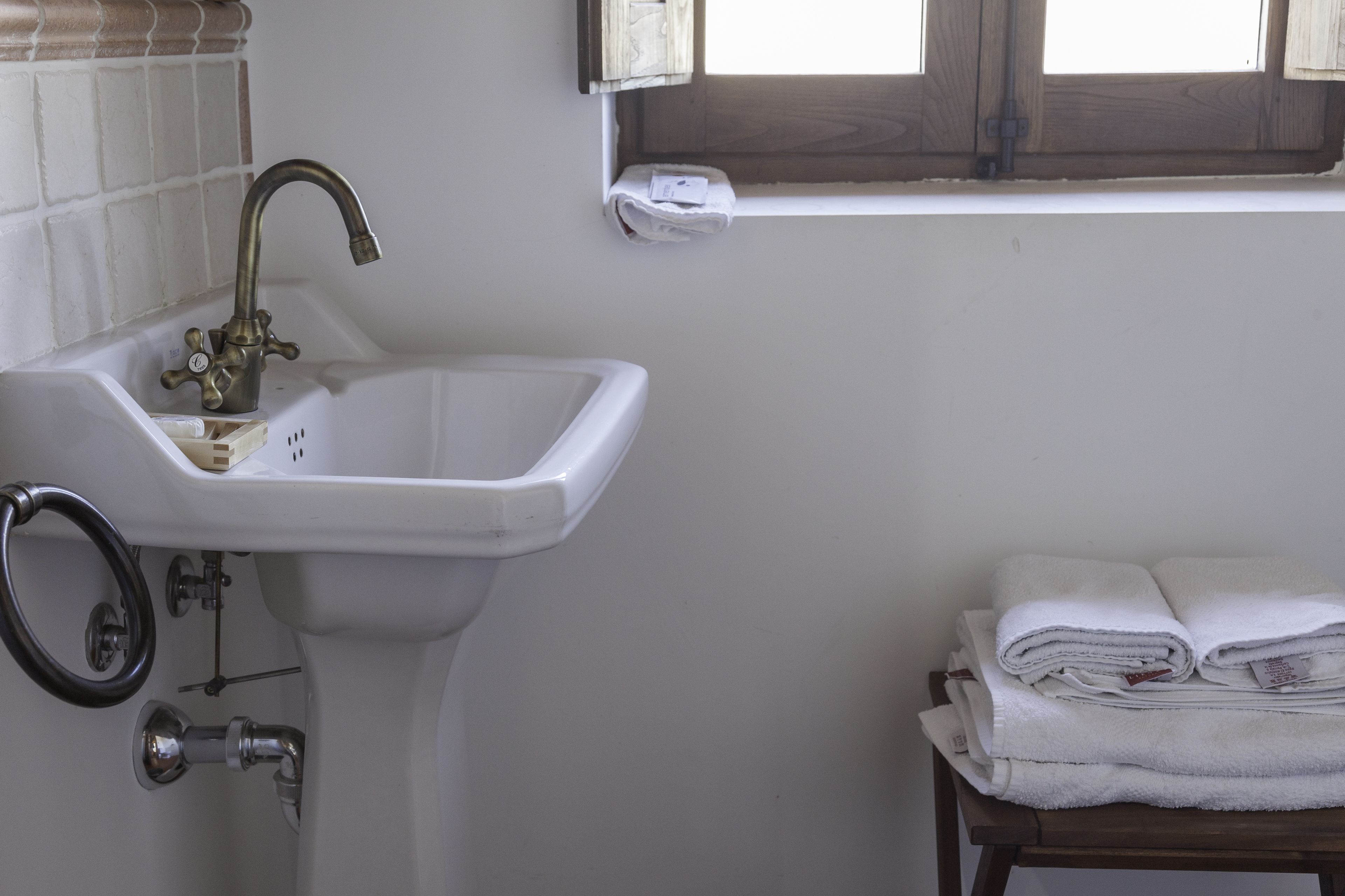 A bathroom with a white sink, a window, and a towel rack.