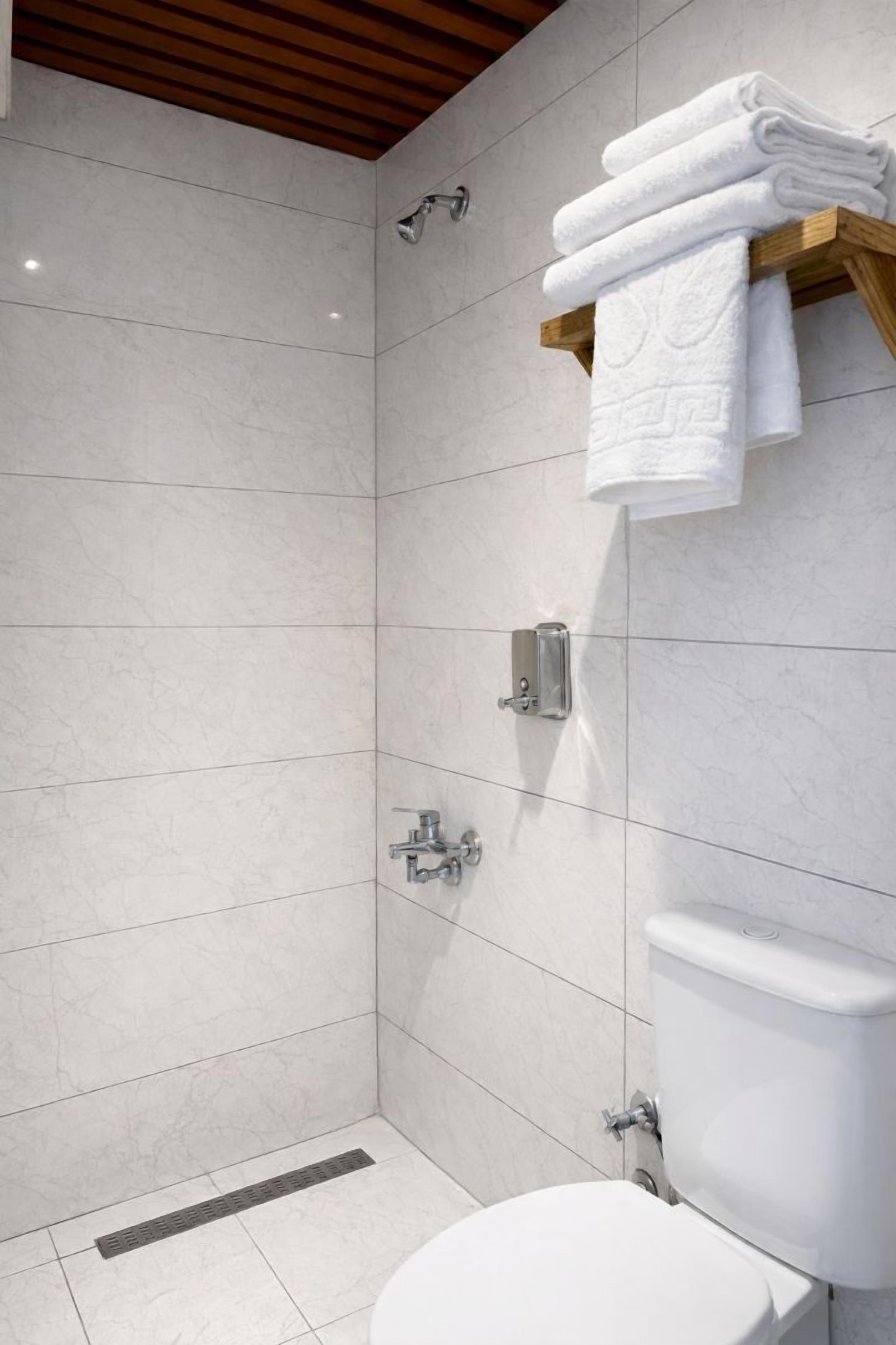 Une salle de bain moderne équipée d’une douche, de toilettes et d’un porte-serviettes.