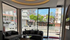 Un hall d’hôtel moderne doté d’un grand espace salon, d’une entrée avec porte vitrée et d’une vue sur la rue.