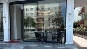 L’extérieur d’un hôtel appelé « Medi Otel », avec une entrée en verre, un espace extérieur aménagé avec des sièges et des marches menant à l’entrée.