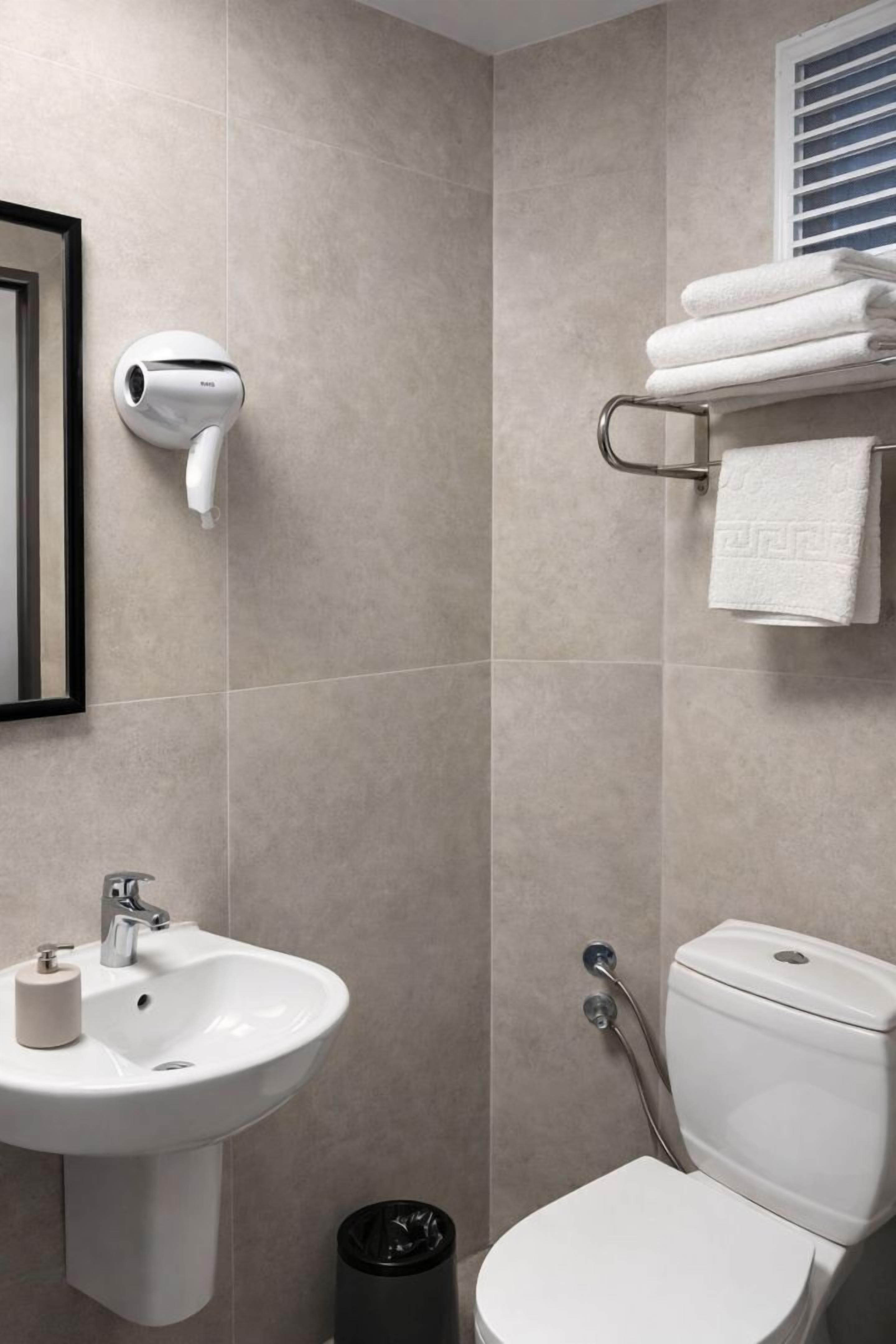 A bathroom with a white sink, toilet, and a towel rack with folded towels.