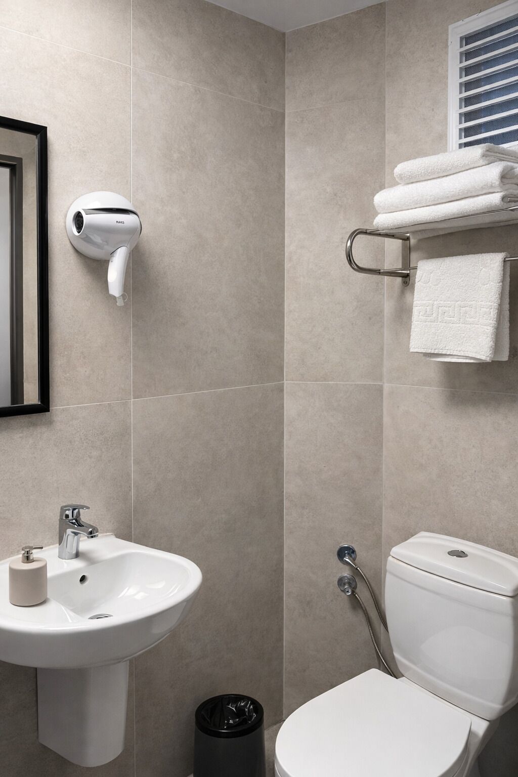 Une salle de bain équipée d’un lavabo, de toilettes et d’un porte-serviettes.