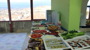 Un bufé con diferentes opciones de comida y vistas a un pueblo costero a través de un ventanal grande.