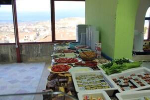 Un bufé con diferentes opciones de comida y vistas a un pueblo costero a través de un ventanal grande.