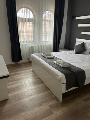 A modern bedroom with a bed, a bedside table, and a window with curtains. -  Loopy Lodge Hotel (Ürgüp)